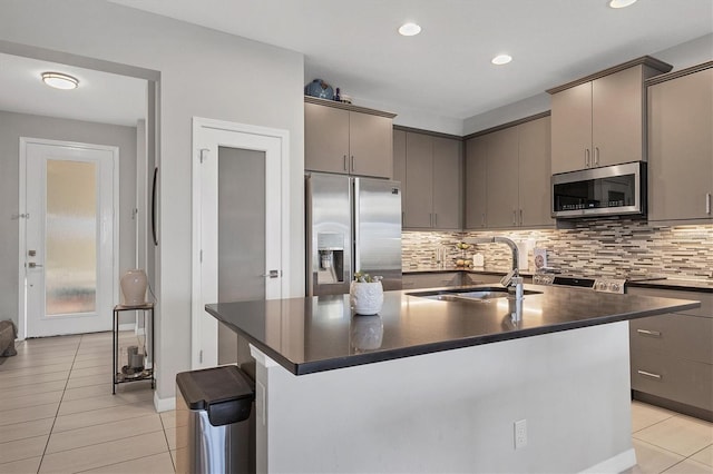 kitchen with appliances with stainless steel finishes, a center island with sink, light tile patterned floors, and sink