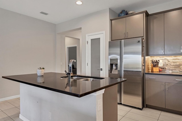 kitchen with a center island with sink, backsplash, sink, and stainless steel refrigerator with ice dispenser