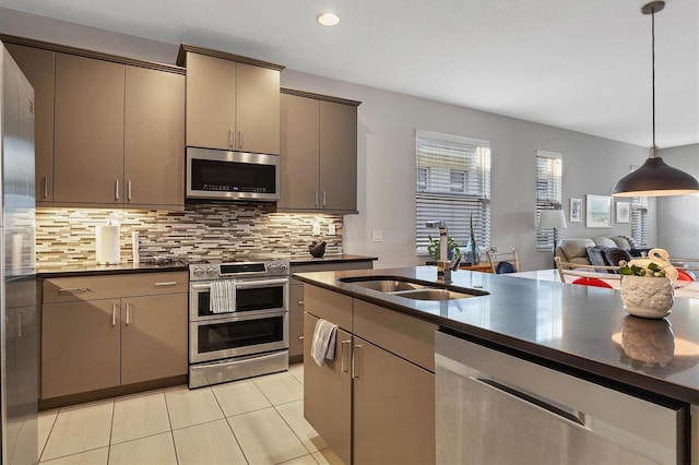 kitchen with appliances with stainless steel finishes, tasteful backsplash, sink, light tile patterned floors, and pendant lighting