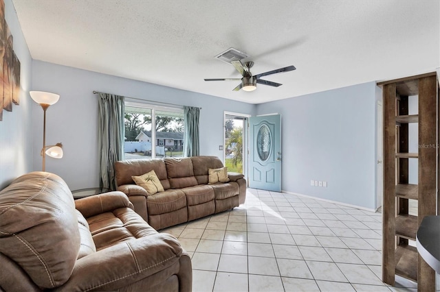 living room featuring ceiling fan, light tile patterned floors, and a textured ceiling