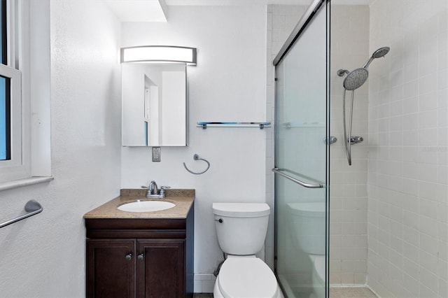 bathroom with an enclosed shower, vanity, and toilet