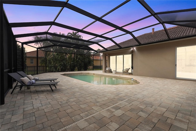 pool at dusk featuring a lanai, a patio area, and an outdoor pool