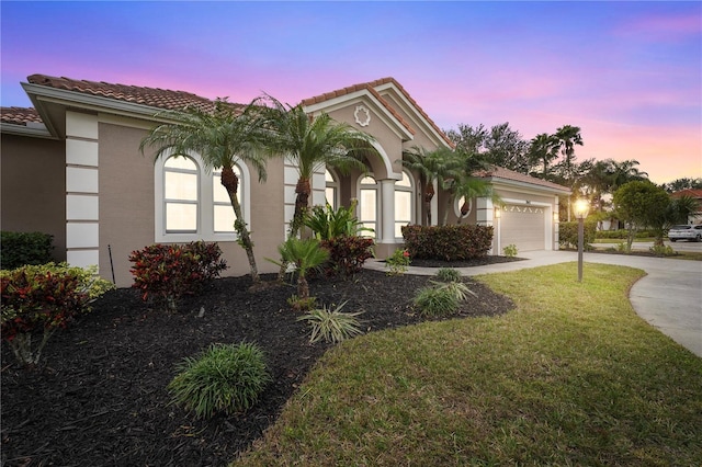 mediterranean / spanish house featuring a garage and a yard