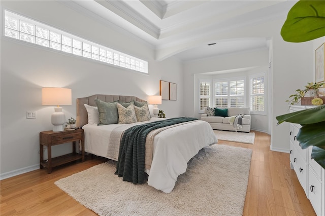 bedroom with ornamental molding, a tray ceiling, light wood-style flooring, and baseboards