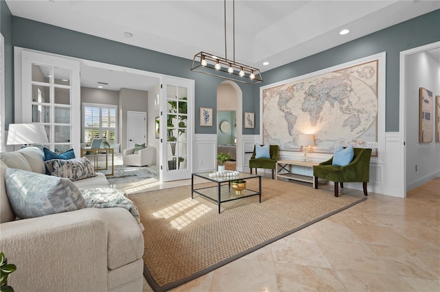 living area featuring arched walkways, a wainscoted wall, tile patterned floors, a decorative wall, and recessed lighting