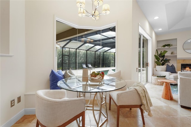 dining space featuring built in shelves, recessed lighting, a sunroom, a warm lit fireplace, and baseboards