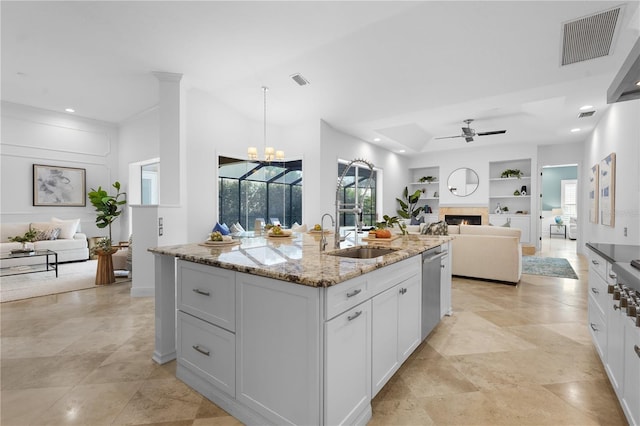 kitchen featuring built in shelves, open floor plan, visible vents, and a sink