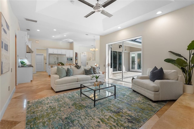 living room with visible vents, baseboards, a raised ceiling, ceiling fan with notable chandelier, and recessed lighting