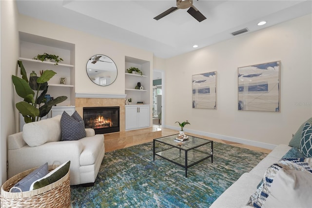 living room with visible vents, built in features, baseboards, a tile fireplace, and recessed lighting