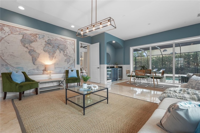 living room with wine cooler, recessed lighting, a wainscoted wall, a decorative wall, and a ceiling fan