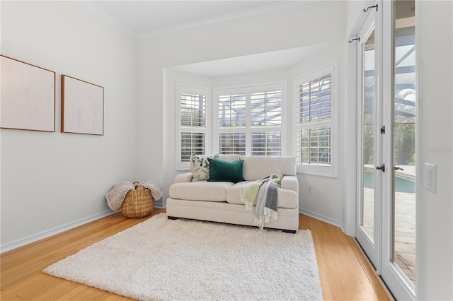 sitting room featuring light wood-type flooring, baseboards, and ornamental molding