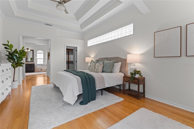 bedroom featuring light wood-type flooring, visible vents, a raised ceiling, and crown molding