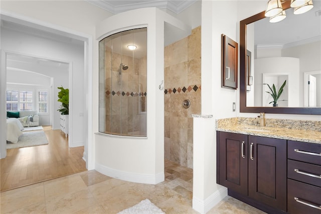 ensuite bathroom with ensuite bathroom, vanity, baseboards, walk in shower, and crown molding