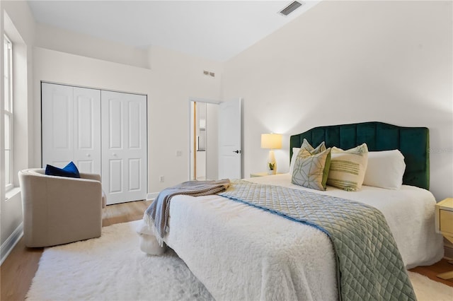 bedroom featuring a closet, wood finished floors, visible vents, and baseboards