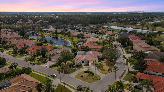 aerial view at dusk with a water view and a residential view