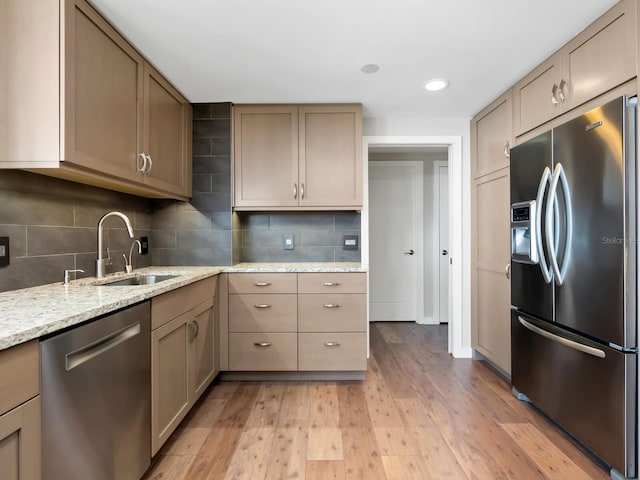 kitchen featuring light stone counters, sink, stainless steel appliances, and light hardwood / wood-style flooring