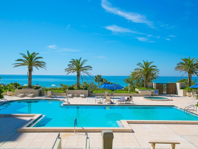 view of pool with a patio area, a community hot tub, and a water view