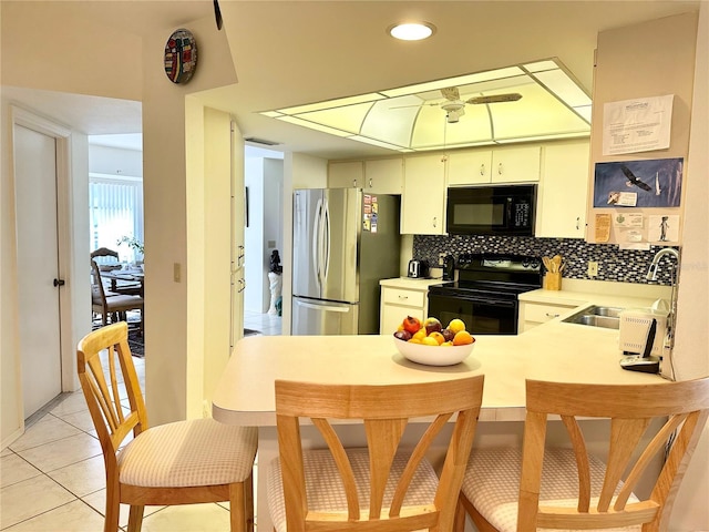 kitchen featuring sink, kitchen peninsula, decorative backsplash, light tile patterned flooring, and black appliances