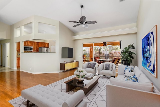 living room with light hardwood / wood-style floors, high vaulted ceiling, and ceiling fan