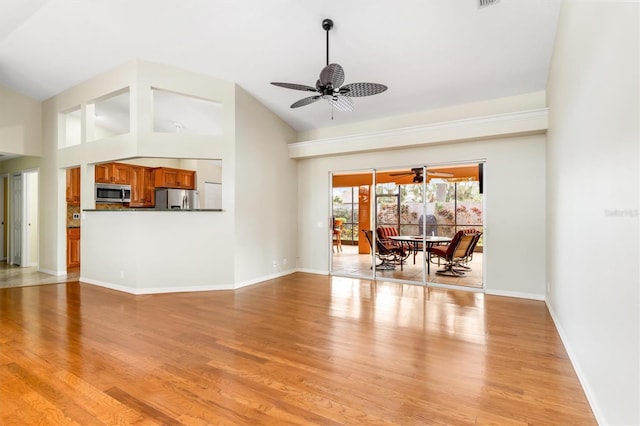 unfurnished living room with ceiling fan, high vaulted ceiling, and light hardwood / wood-style flooring