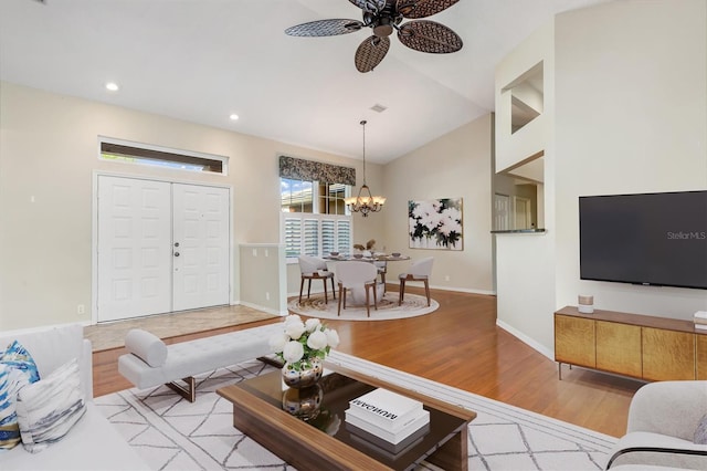 living room featuring ceiling fan with notable chandelier, lofted ceiling, and light hardwood / wood-style floors