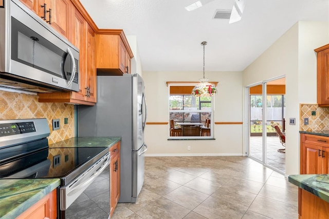 kitchen with lofted ceiling, hanging light fixtures, light tile patterned floors, appliances with stainless steel finishes, and backsplash