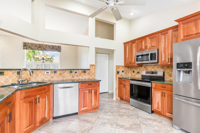 kitchen featuring sink, light tile patterned floors, a towering ceiling, stainless steel appliances, and ceiling fan with notable chandelier