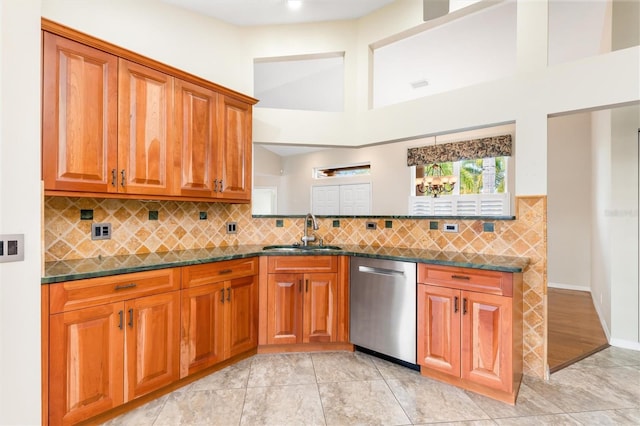 kitchen featuring light tile patterned flooring, sink, dark stone countertops, dishwasher, and a high ceiling