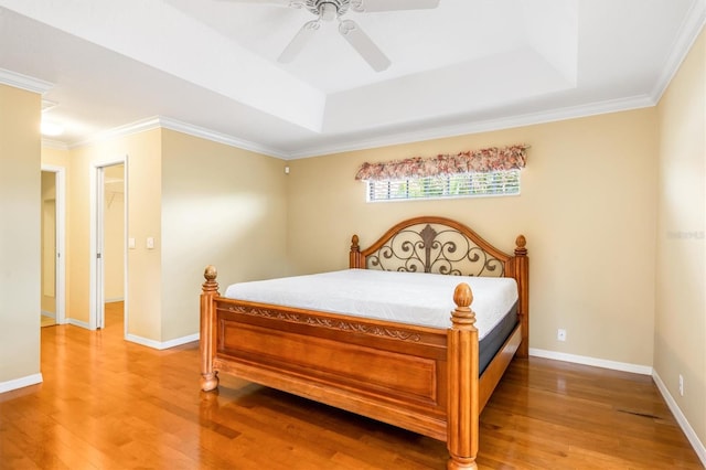 bedroom with a raised ceiling, ornamental molding, hardwood / wood-style floors, and ceiling fan