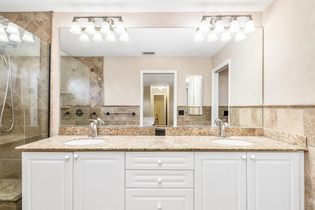 bathroom featuring tiled shower, vanity, and tile walls