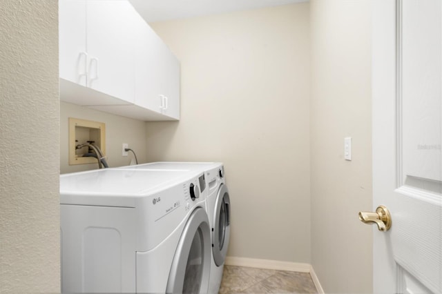 laundry area featuring light tile patterned floors, washer and clothes dryer, and cabinets