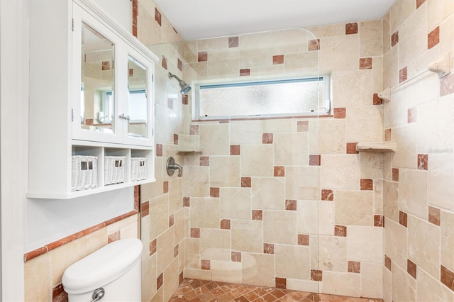 bathroom with toilet, tile walls, and a tile shower