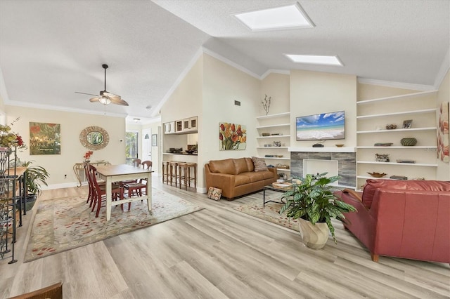 living room featuring ornamental molding, a textured ceiling, a skylight, and wood finished floors