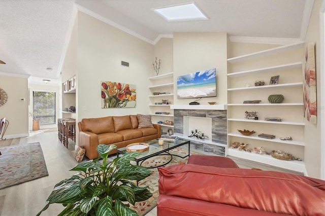 living room with ornamental molding, a textured ceiling, wood finished floors, a skylight, and a premium fireplace