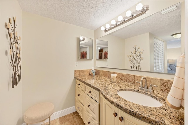 bathroom with vanity, baseboards, visible vents, tile patterned flooring, and a textured ceiling