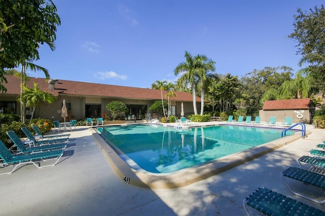 community pool featuring a patio and an outbuilding