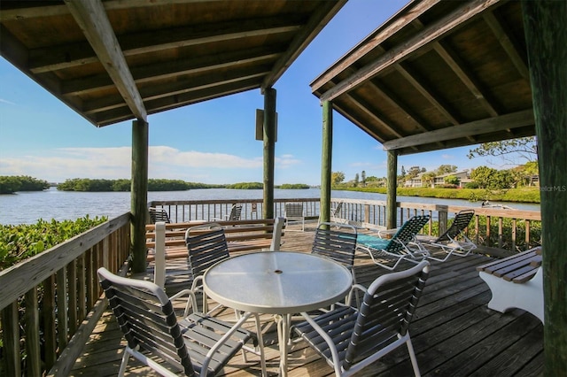 wooden terrace featuring outdoor dining space and a water view