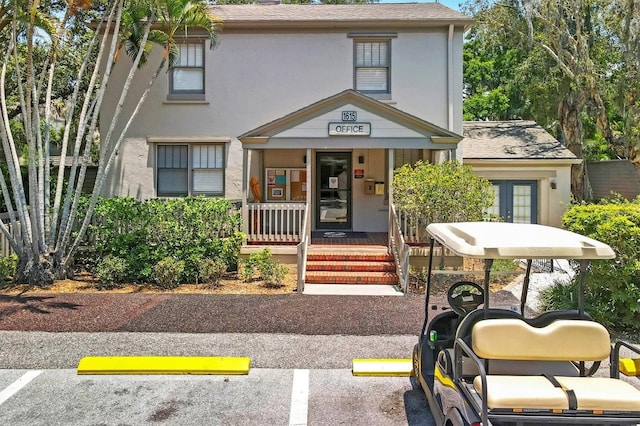 view of front of home featuring stucco siding, roof with shingles, and uncovered parking