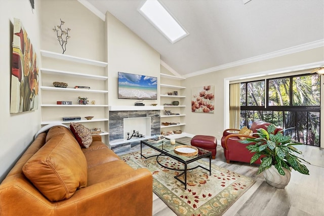 living room with built in features, wood finished floors, vaulted ceiling with skylight, a fireplace, and crown molding