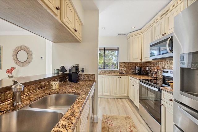 kitchen with cream cabinetry, tasteful backsplash, appliances with stainless steel finishes, and a sink