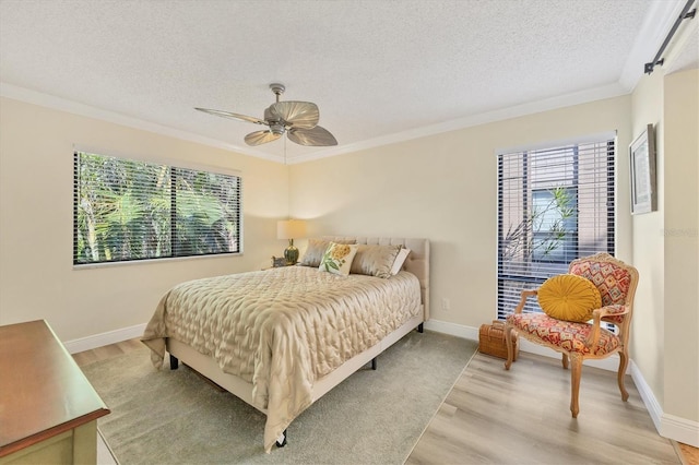 bedroom with multiple windows, a textured ceiling, crown molding, and light wood finished floors