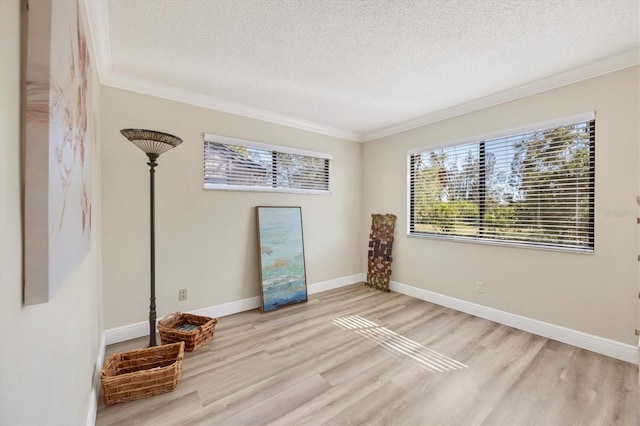 empty room featuring baseboards, a textured ceiling, wood finished floors, and crown molding