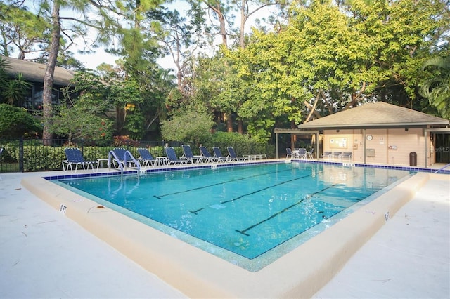 pool with a patio area and fence