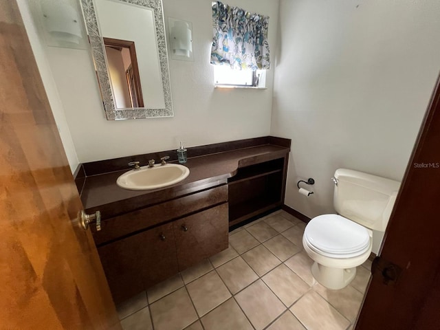 bathroom with toilet, vanity, and tile patterned floors