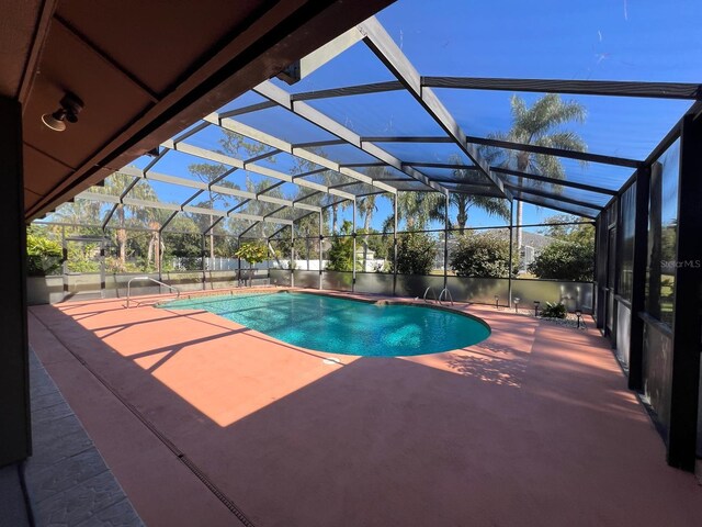 view of swimming pool featuring a patio and glass enclosure