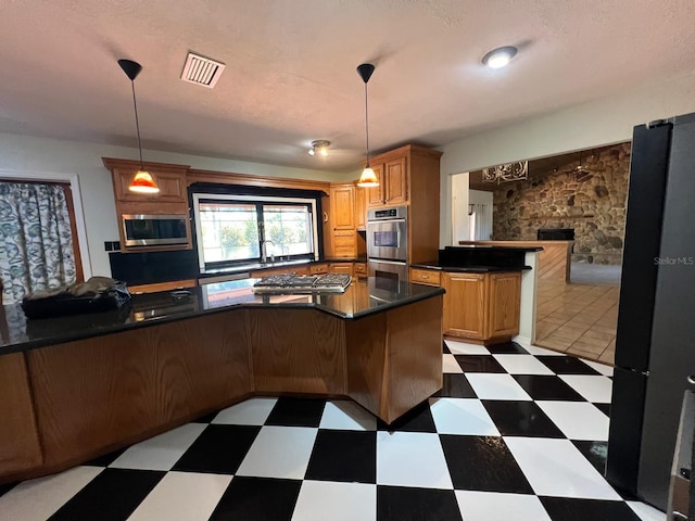 kitchen with pendant lighting, kitchen peninsula, a textured ceiling, and appliances with stainless steel finishes