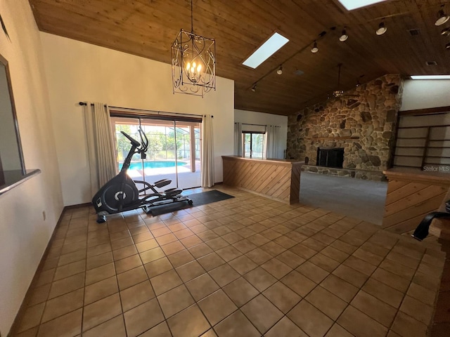 exercise area featuring a skylight, wooden ceiling, an inviting chandelier, tile patterned flooring, and a fireplace