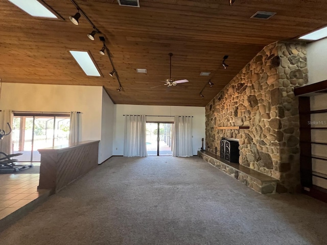 unfurnished living room with ceiling fan, a stone fireplace, high vaulted ceiling, carpet floors, and track lighting