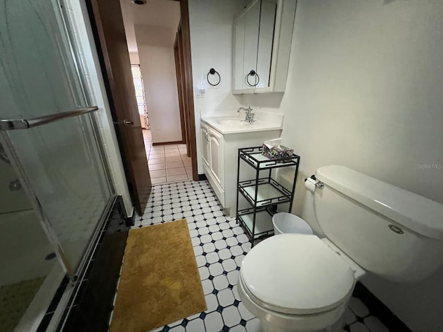 bathroom featuring vanity, toilet, and a shower with door