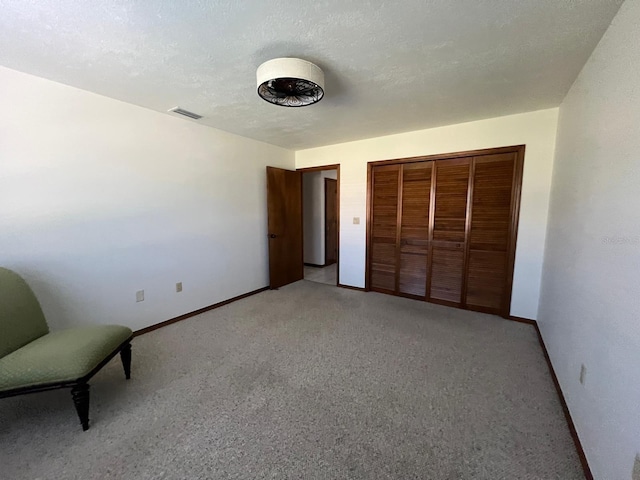 unfurnished bedroom featuring light colored carpet, a textured ceiling, and a closet